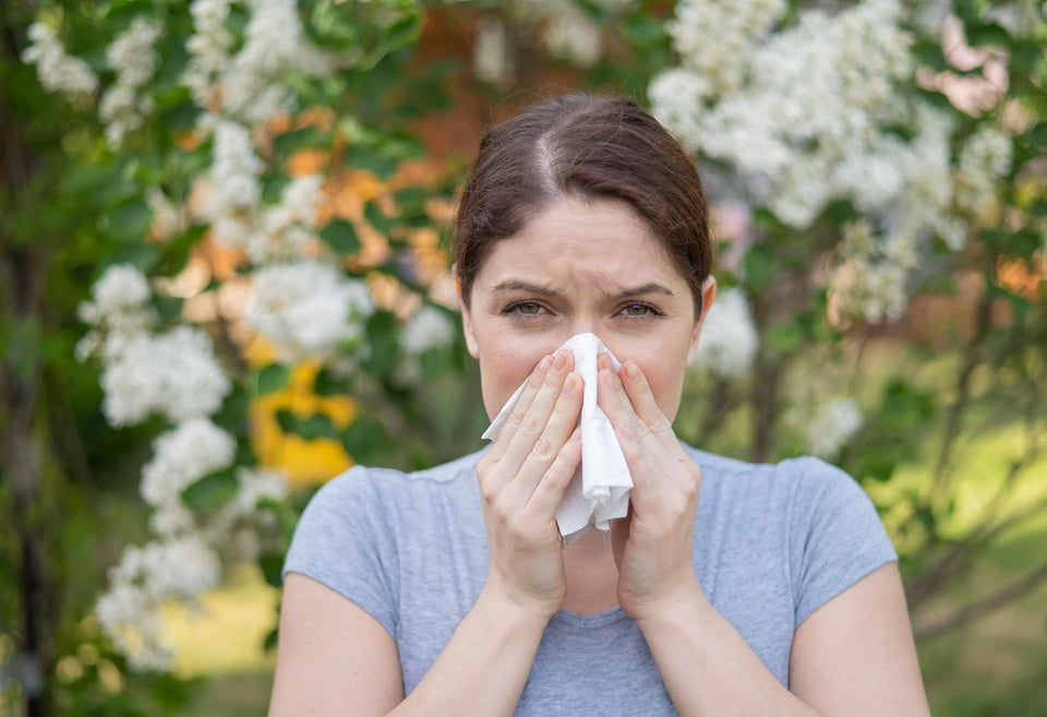 A woman sneezing from allergies outdoors